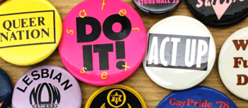 A color photograph close up of various buttons with slogans on them, such as Lesbian Rights, Queer Nation, Act up!, Safer Sex: Just do it