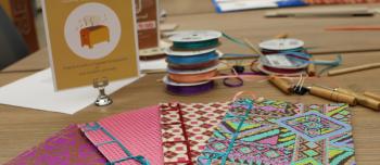 Colorful handmade books on a workshop table surrounded by ribbon and tools