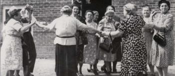 A group of Jewish women gather in a circle, holding hands and dancing