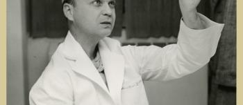 Man in a lab coat holds up an image