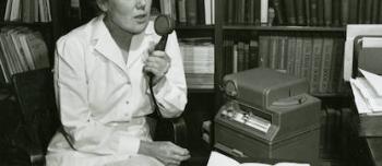 Gertrude Gilman speaking into a microphone