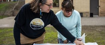 Julliette Dannucci learns about the racial covenant on her home with Rebecca Gillette, the Mapping Prejudice community engagement lead, at Sanborn Park in Robbinsdale, Minnesota, on Friday, May 3, 2024. (Photo/Adria Carpenter)