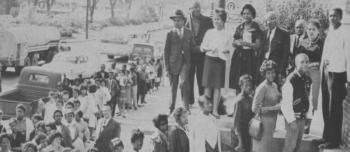The photo is an excerpt from the Southern Christian Leadership Conference brochure, "Crusade for the Vote" It shows a line of young, Black women and men in line to register to vote in Macon, GA. The line goes up down the steps and along the sidwalk.  