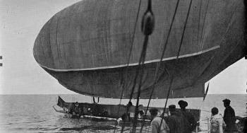Black and white photo of a retired airship on the water.