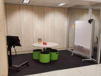 Study alcove with tables and stools, whiteboard, and rolling monitor