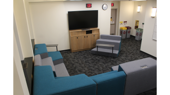 Semi private space with L shaped seating arrangement and large mounted monitor. 