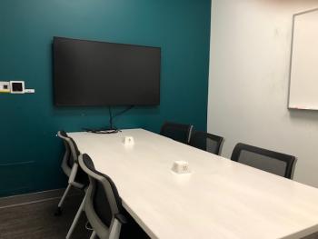 Long table and chairs, white board, and TV screen with screen casting control panel