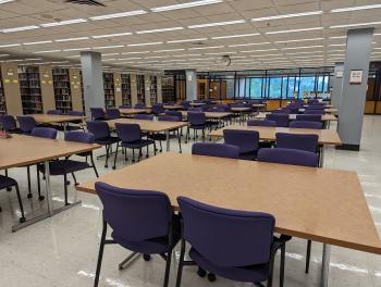 Several tables with chairs surrounded by shelves of books.
