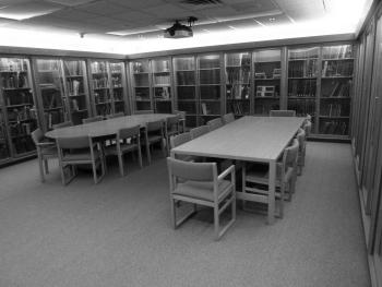 Two wooden tables with chairs surrounded by book cases