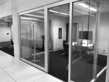 Glass walled study room with table, chairs, monitor and whiteboard